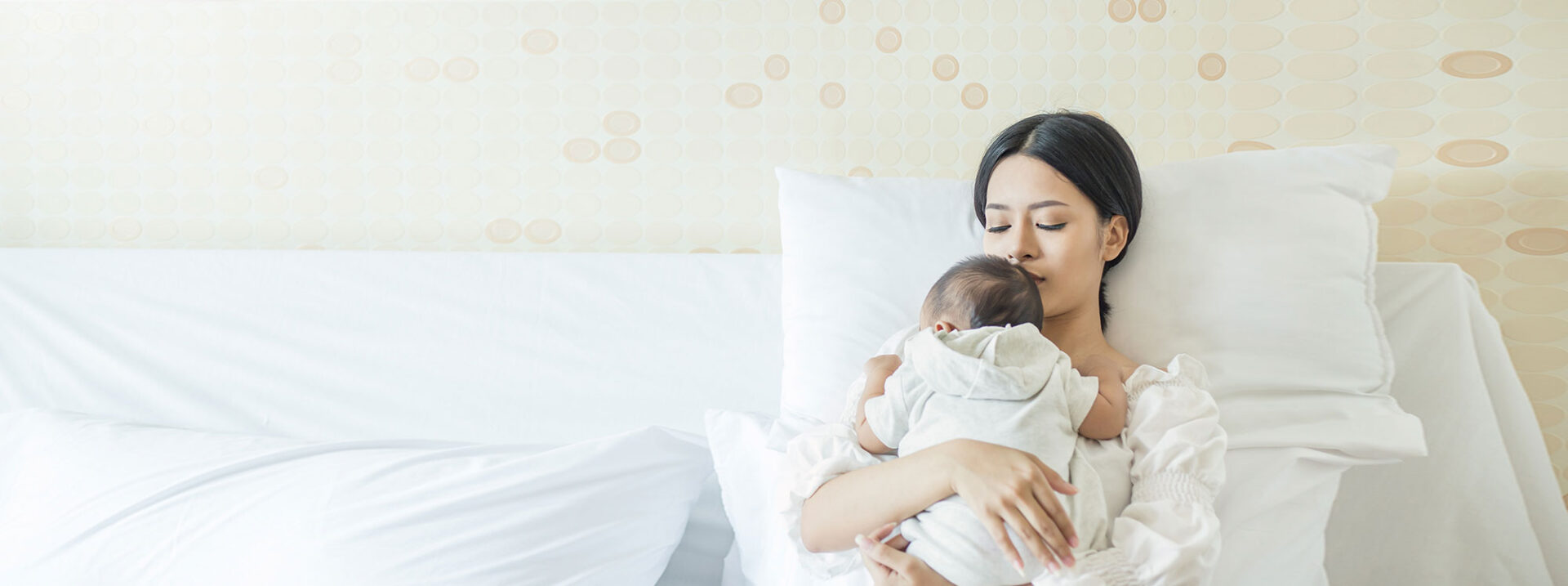 Close up portrait of beautiful young asian mother with newborn baby, copy space with bed in the hospital. Healthcare and medical love lifestyle mother's day concept