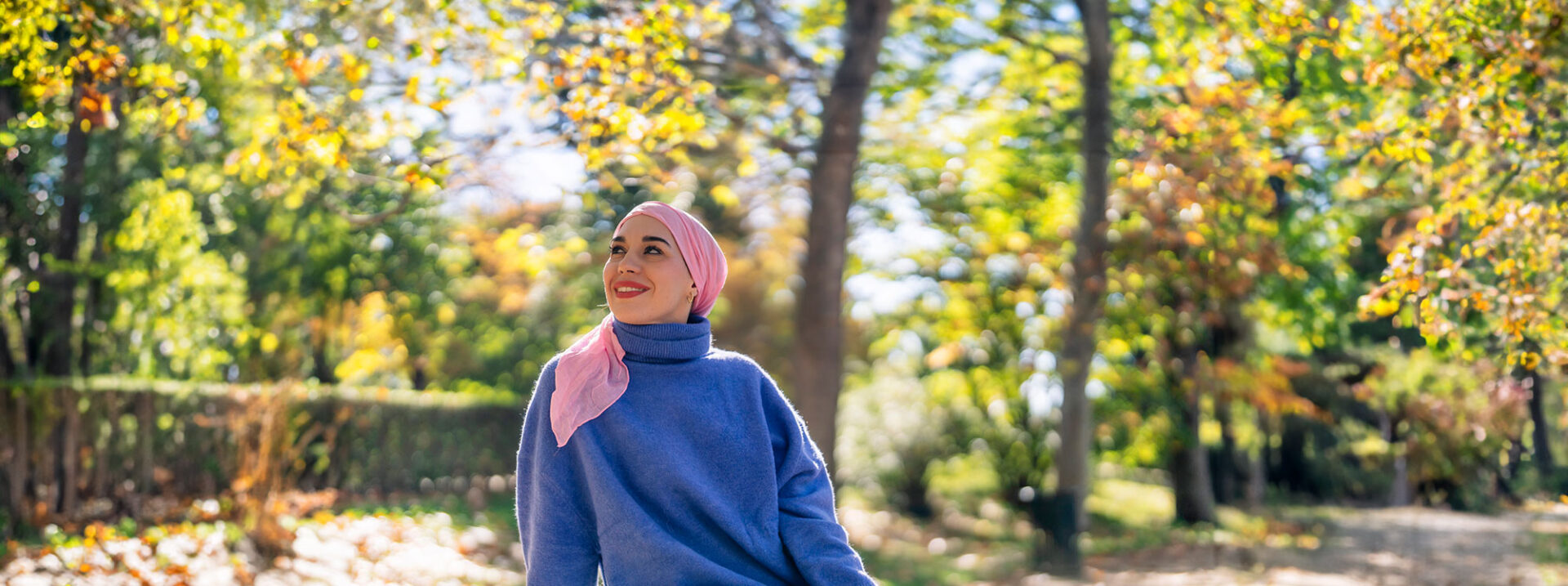 Confident woman in the forest for breast cancer awareness against urban background
